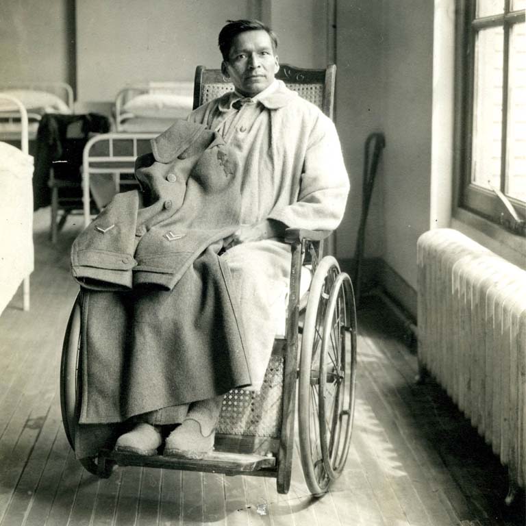 Soldier sitting in a wheel chair with his jacket on his lap showing his rank.