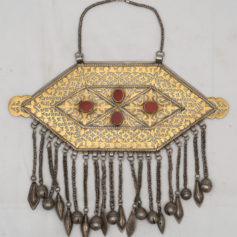 Golden flattened hexagon with fire designs. Four red stones on the front in a diamond pattern. There are silver bells hanging from the shape.