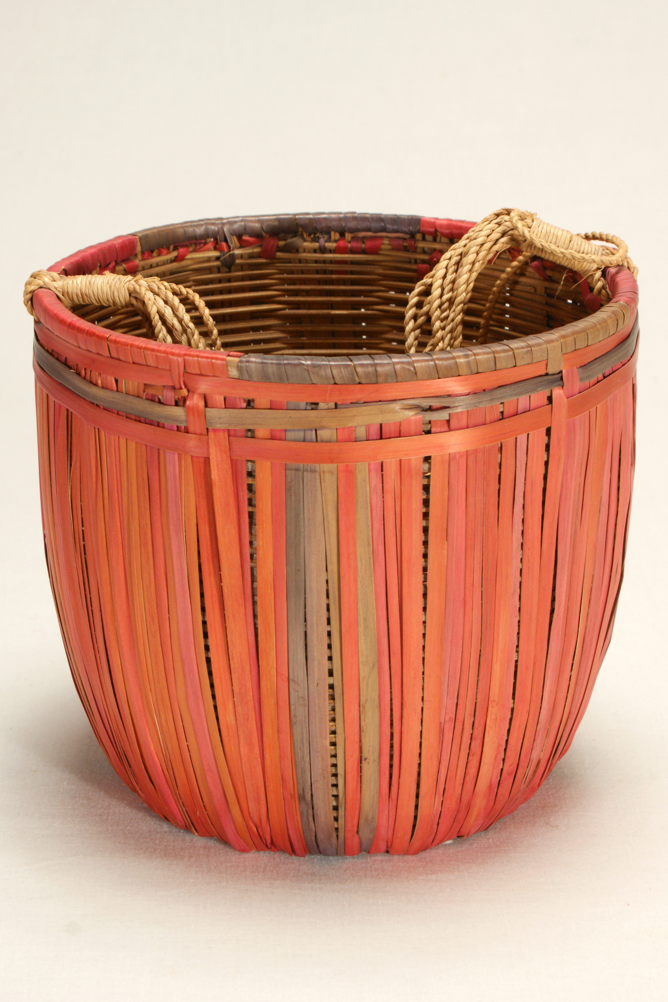 Fuchsia and green basket made of splint wood with a fiber handle.